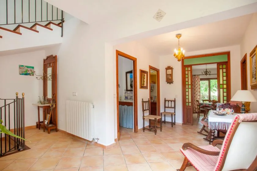 A bright interior hallway opens onto a dining area, with stairs and seating nearby.