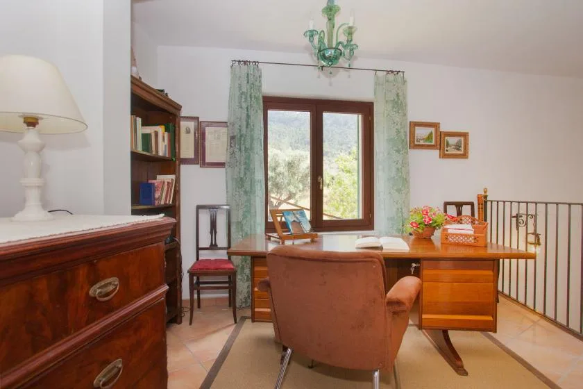 A study with a desk and seating beside a large window.