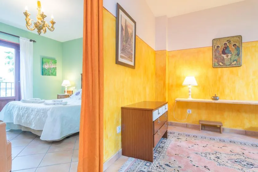 A bedroom and adjoining sitting area with colorful walls and a bed.