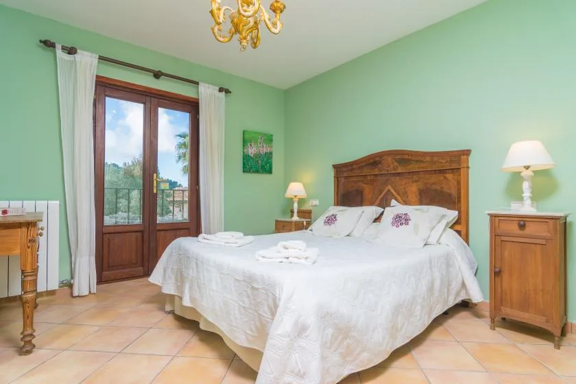 A bedroom with a large bed, wooden headboard, and glass doors opening to a balcony.