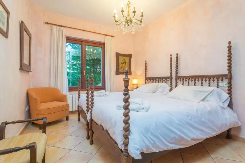 A bedroom with a large bed, an armchair, and a window with curtains.