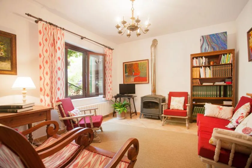 A living room with red seating, a bookcase, and a wood-burning stove.