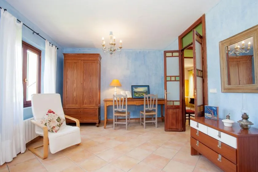 A furnished room with a white armchair, wooden cabinet, and desk.