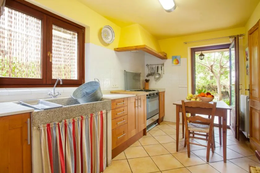 A bright kitchen with wooden cabinets, a sink, and a dining table by the window.
