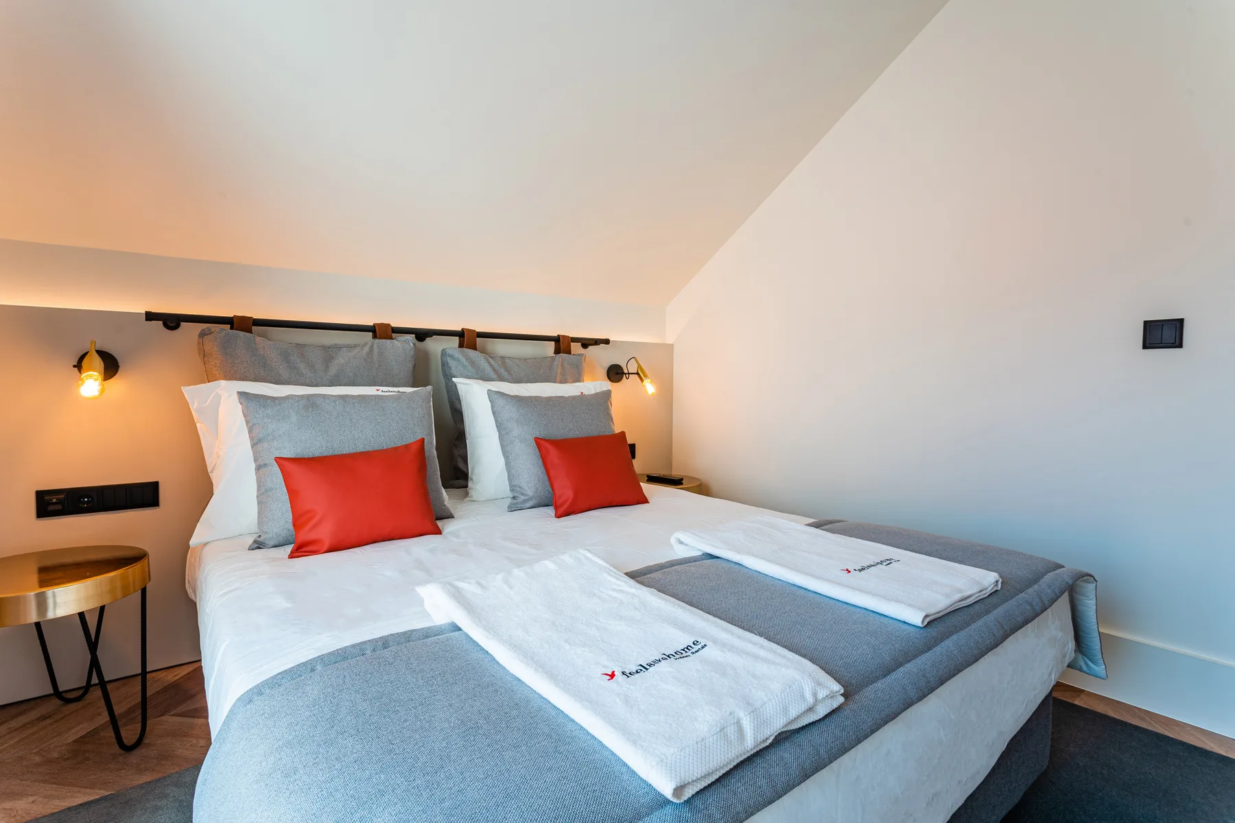 A bedroom with two neatly made beds and warm bedside lighting.