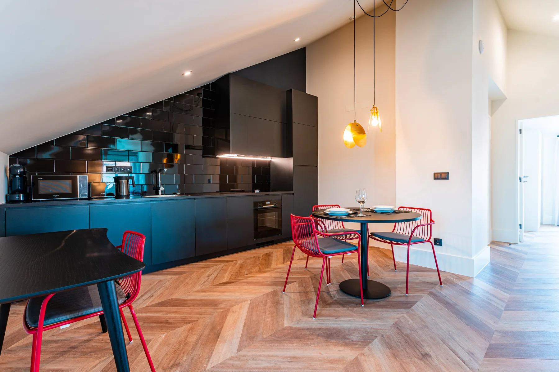 A modern kitchen and dining area with a dark counter and red seating.