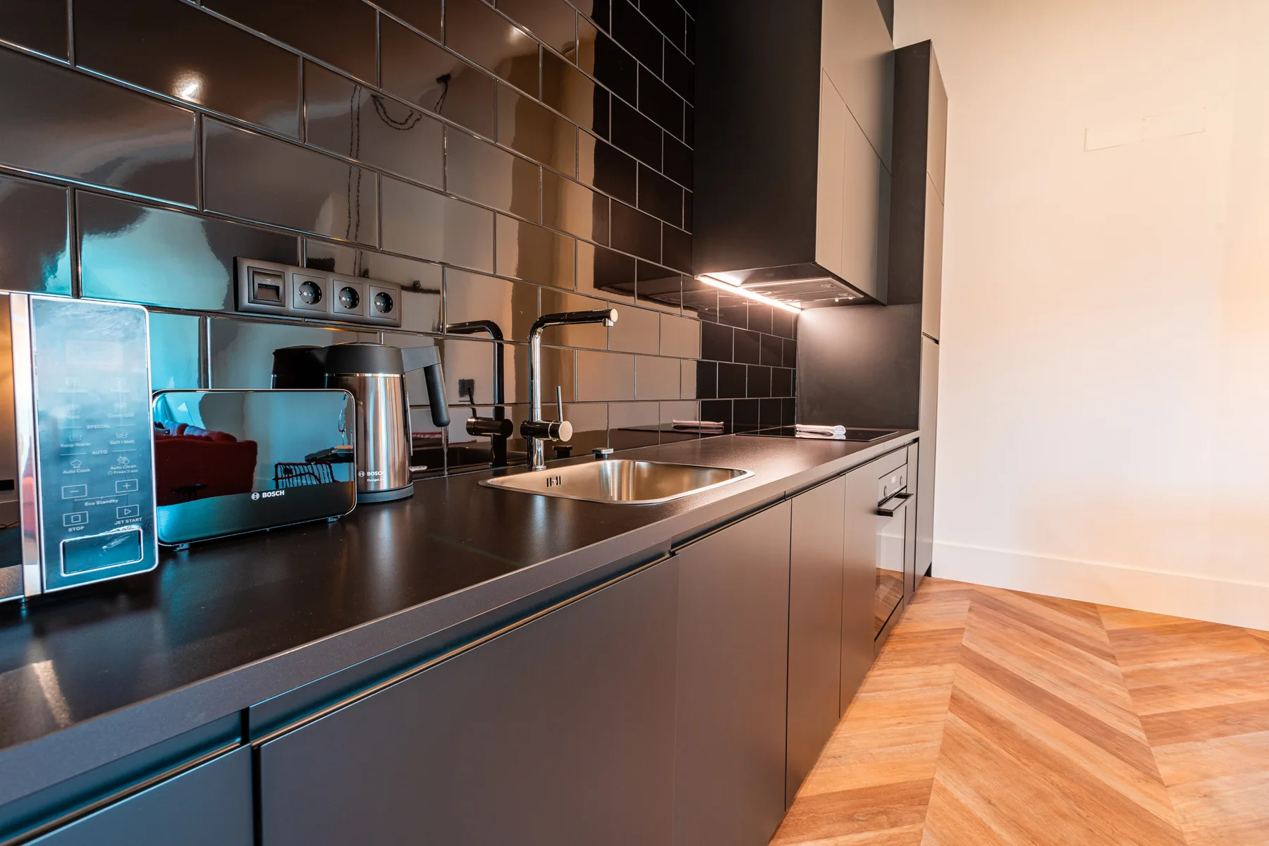 A modern kitchen with dark cabinets and a stainless-steel sink.