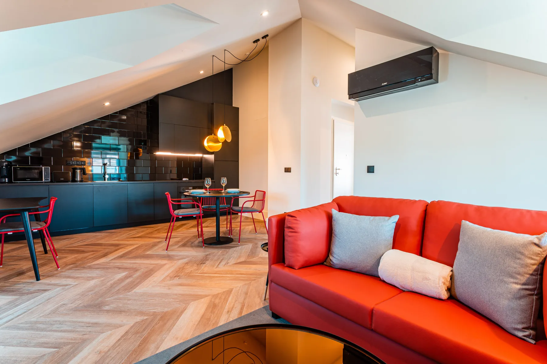 Living room with red seating beside an open kitchen and dining area.