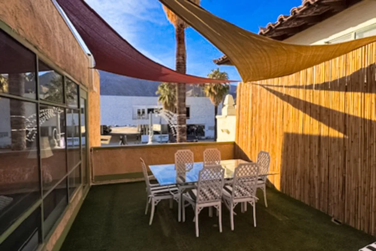 An outdoor dining area with a table and chairs beneath shade sails.