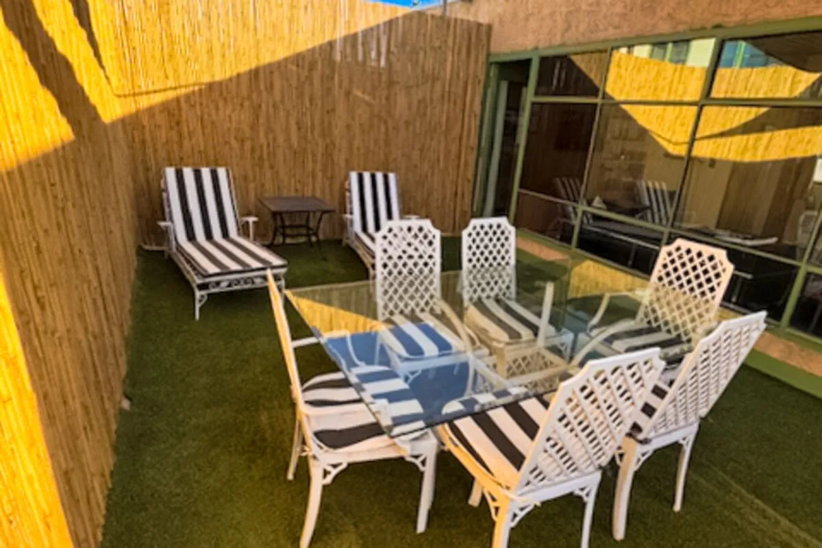 An outdoor seating area with white chairs and a glass-topped table.