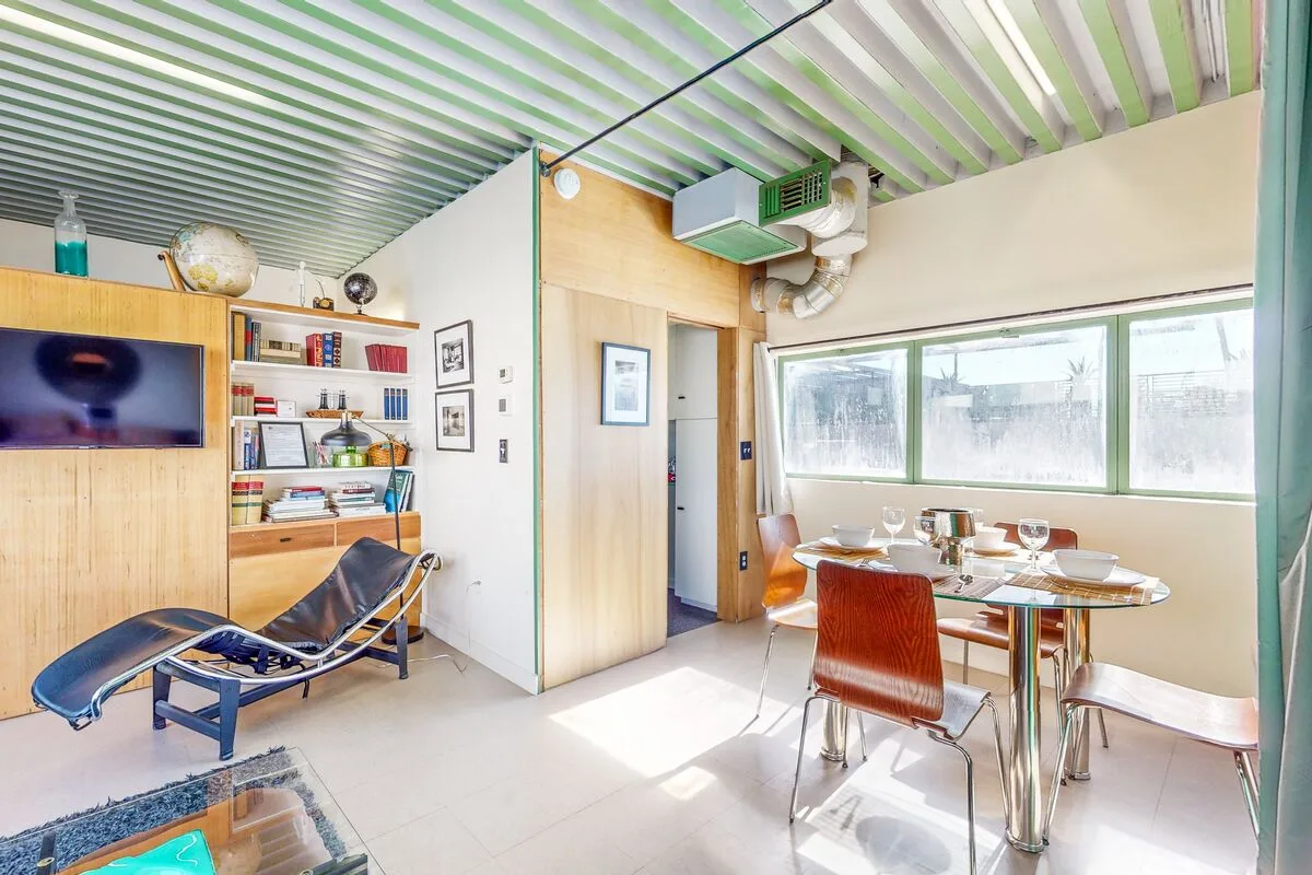 A bright dining and sitting area with a table beside wide windows.