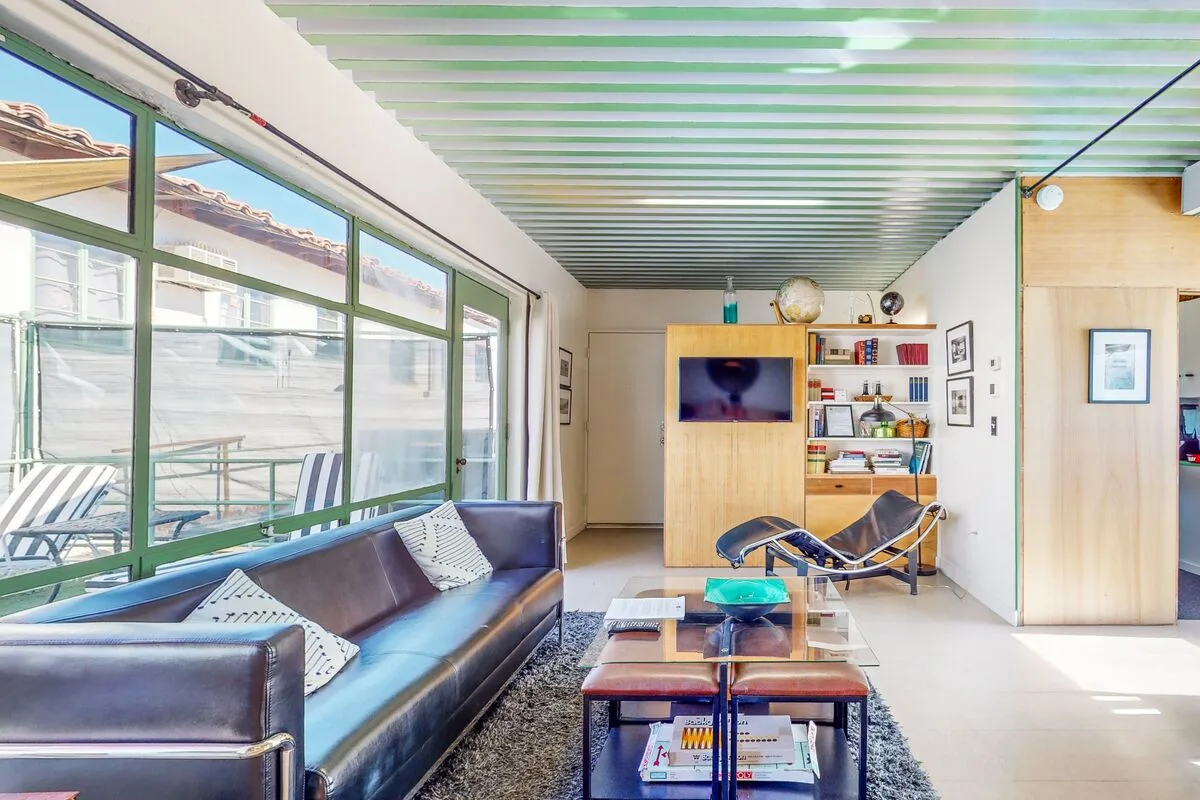 A bright living room with seating, a coffee table, and large windows.