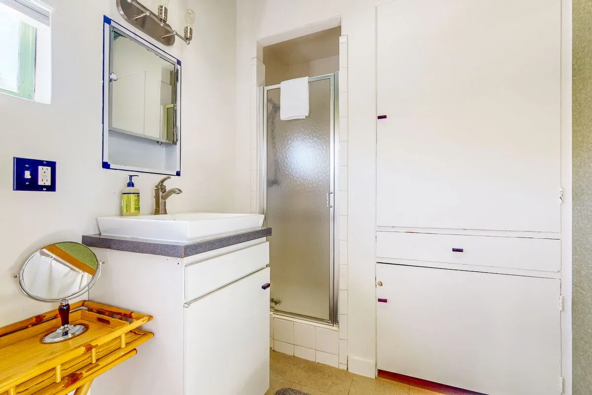 A bathroom with a sink, mirror, and glass shower.