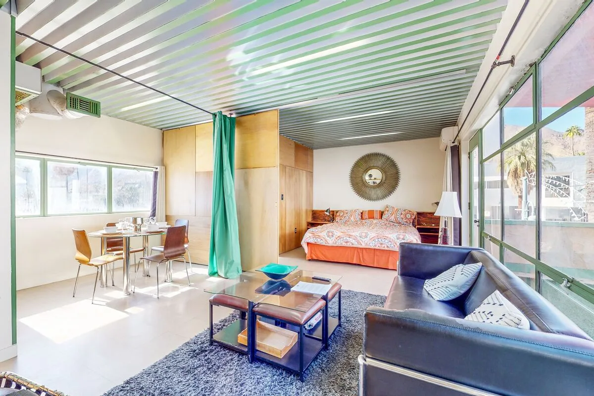 A bright studio room combines a sleeping area, dining table, and lounge seating.