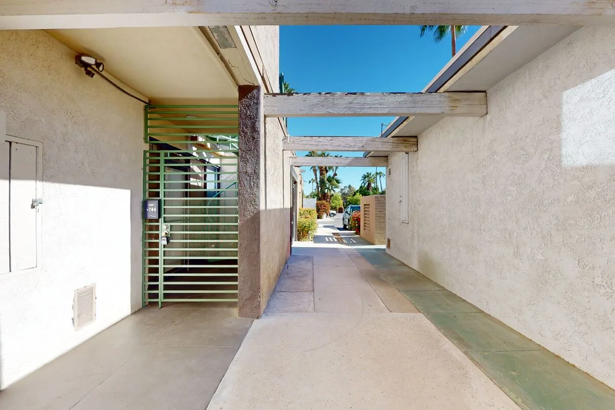 A covered outdoor passage leads toward a sunlit courtyard.