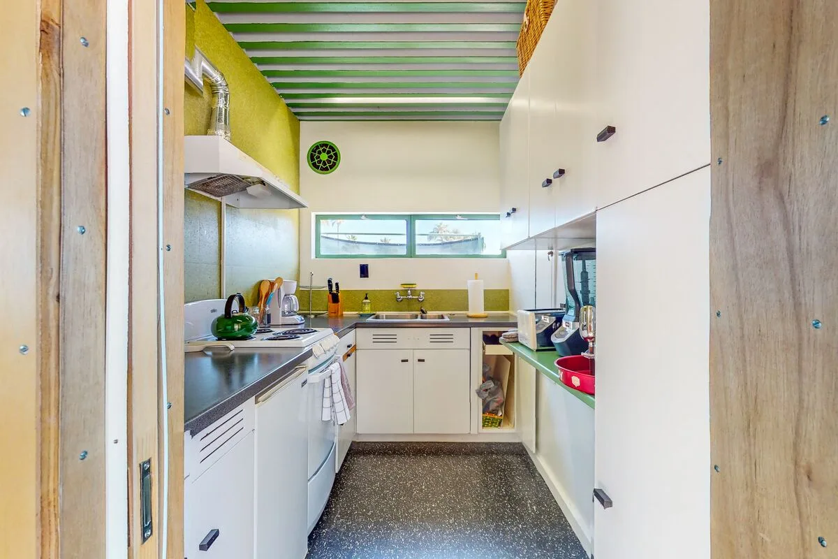 A narrow kitchen with white cabinetry, stainless counters, and a central work area.