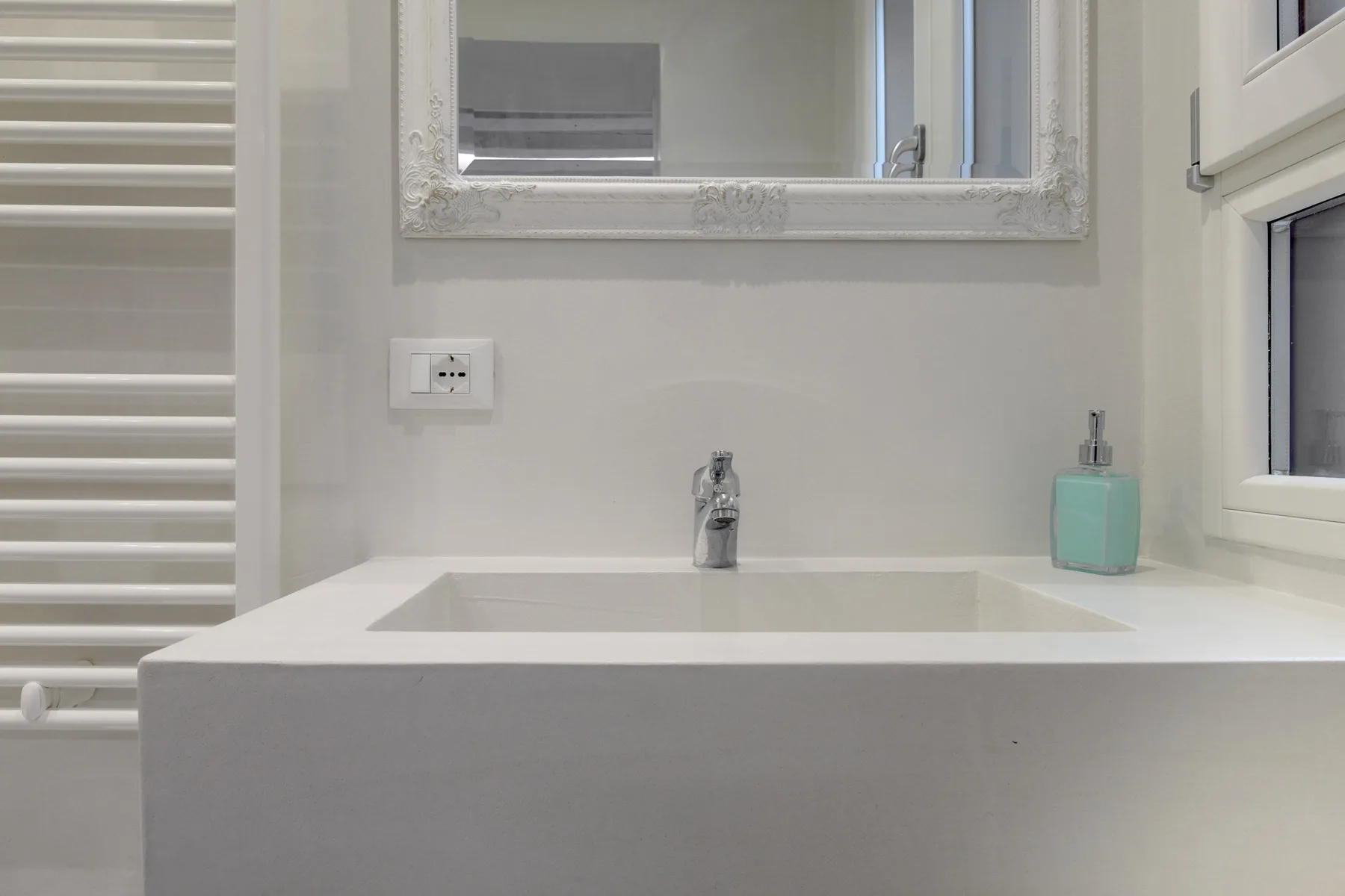 Un lavabo de baño con espejo de pared y dispensador de jabón.