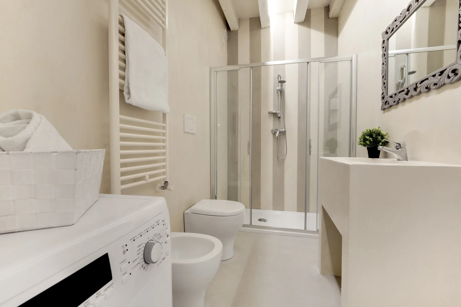 Un baño luminoso con ducha de cristal y lavadora.