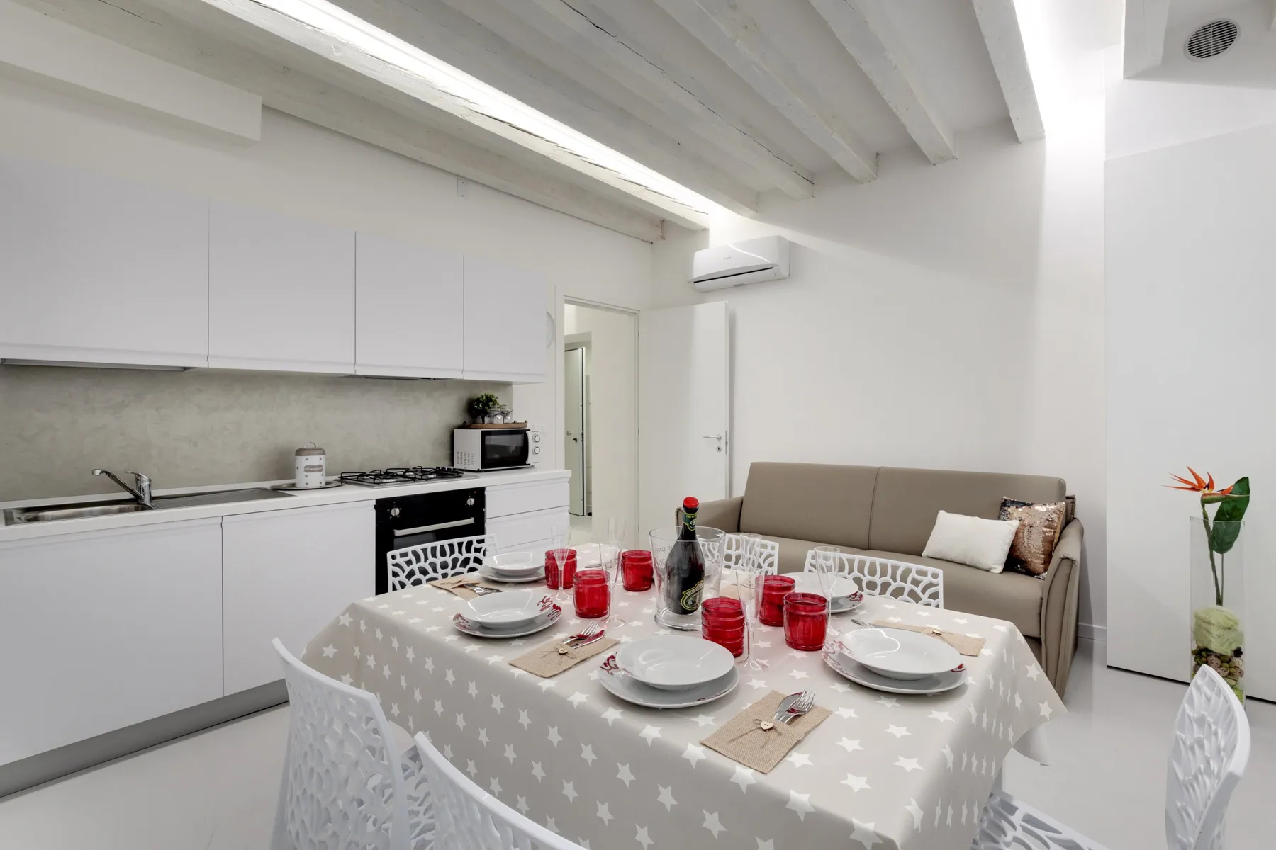 Comedor con la mesa puesta junto a una cocina compacta y asientos.