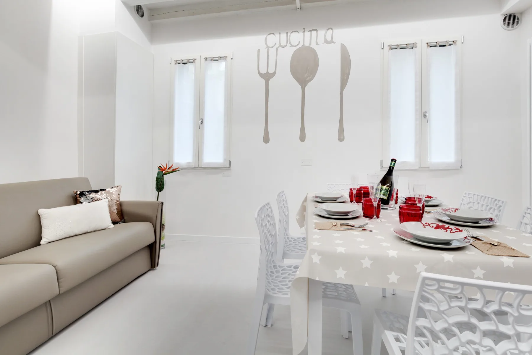 Un comedor luminoso con la mesa puesta y un sofá cerca.
