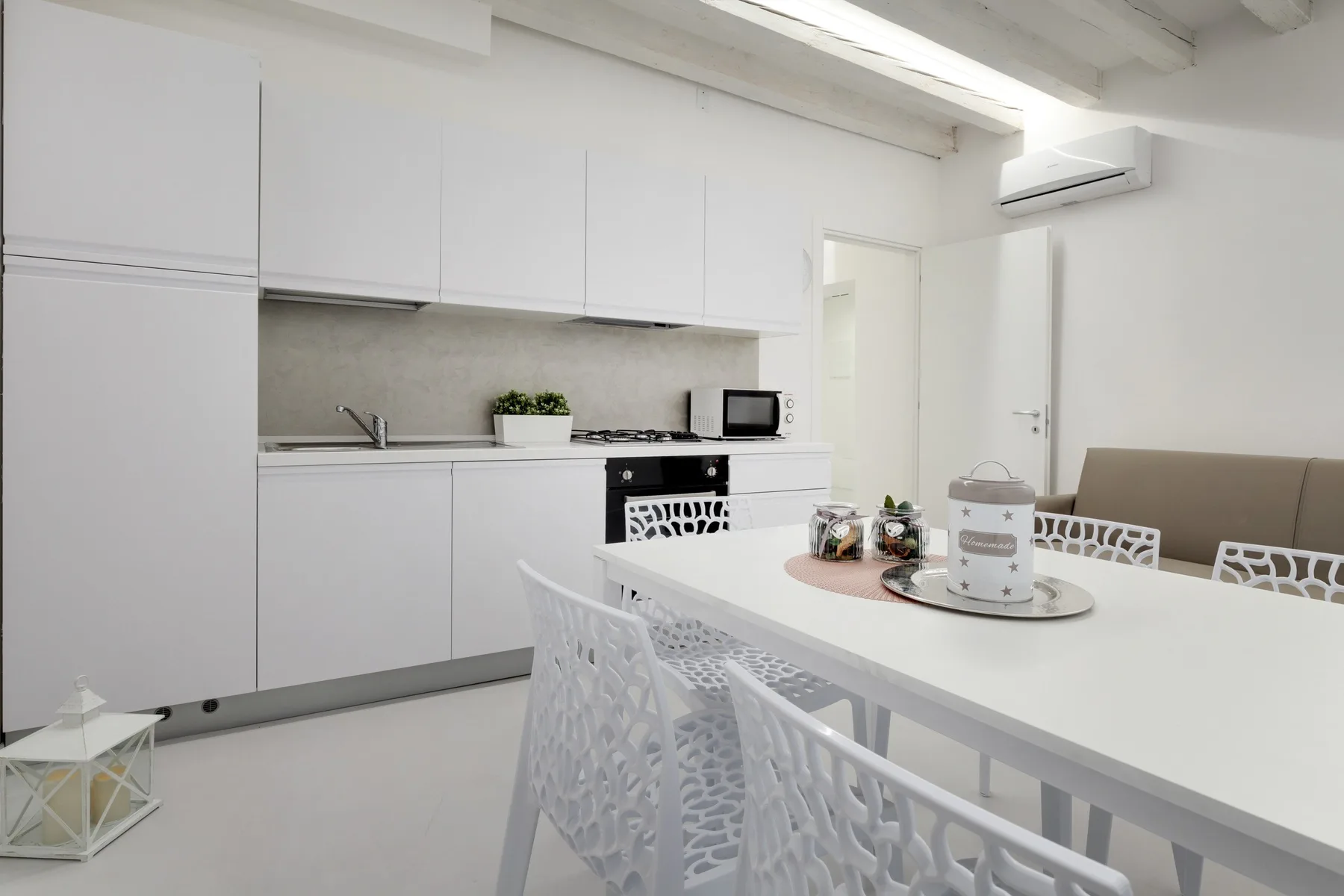Una cocina luminosa con comedor, muebles blancos y una mesa larga.