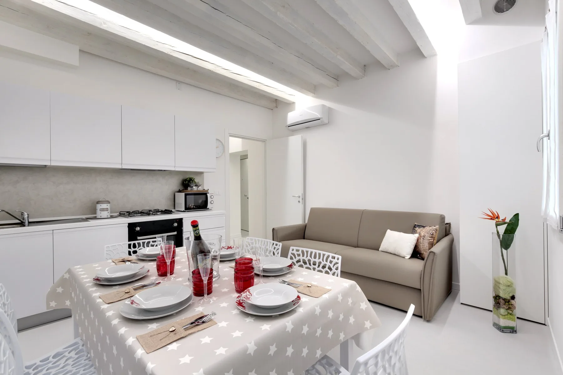 Una cocina y comedor luminosos, con la mesa puesta junto a un sofá.