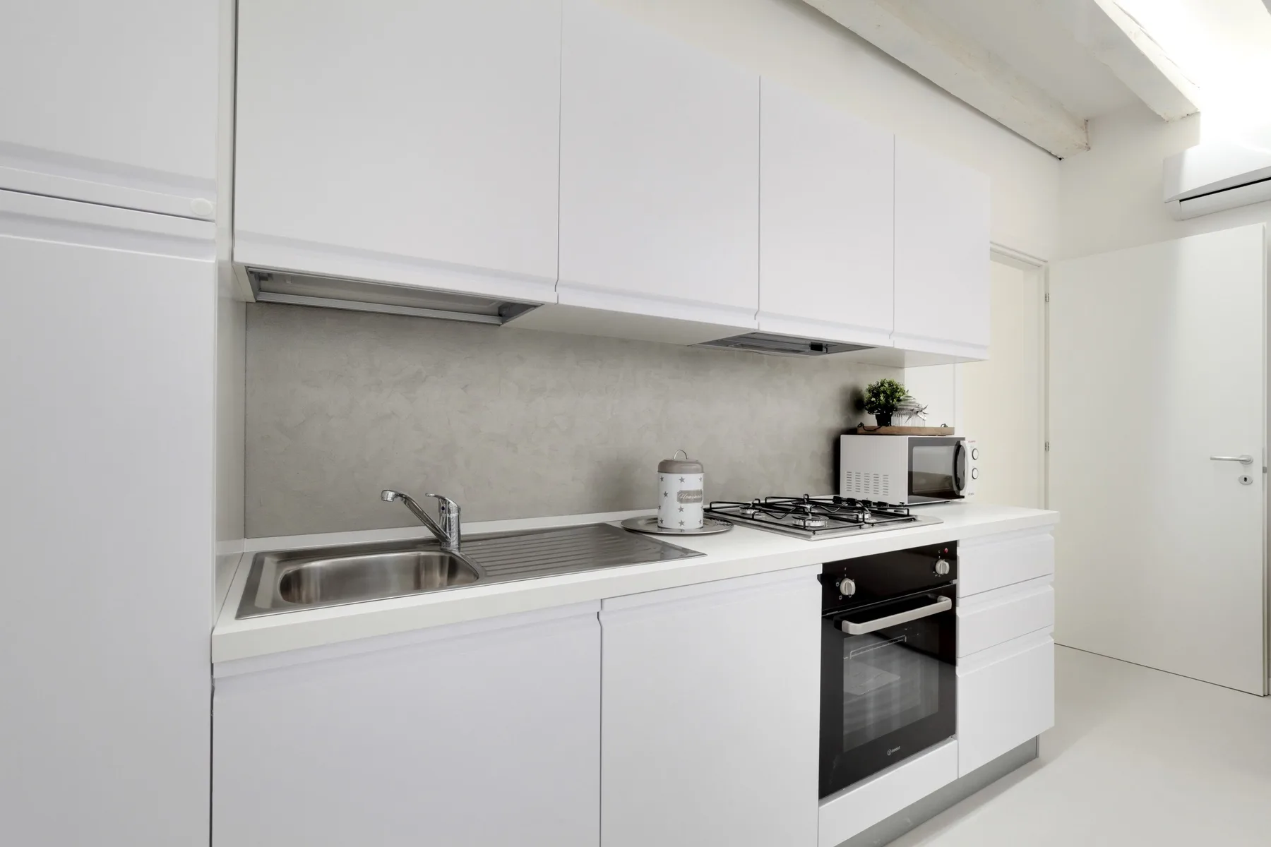 Una cocina luminosa con gabinetes blancos, un fregadero y un horno empotrado.