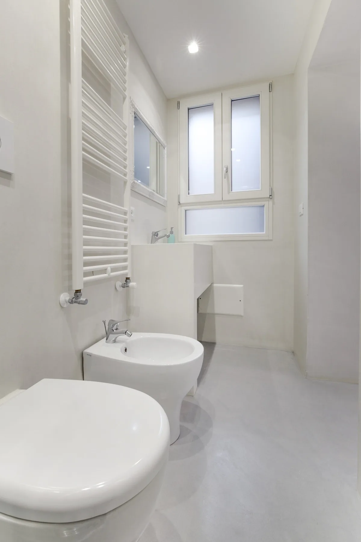 Un baño luminoso con bañera, bidé y una ventana alta.
