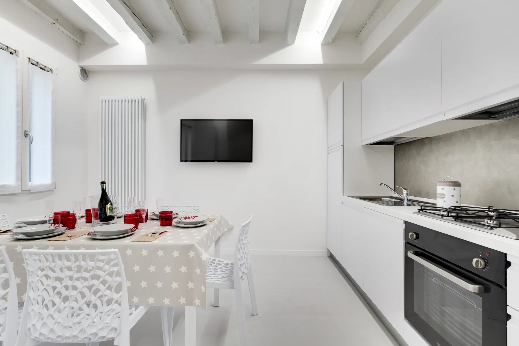 Una cocina luminosa con comedor y una mesa puesta bajo vigas expuestas.