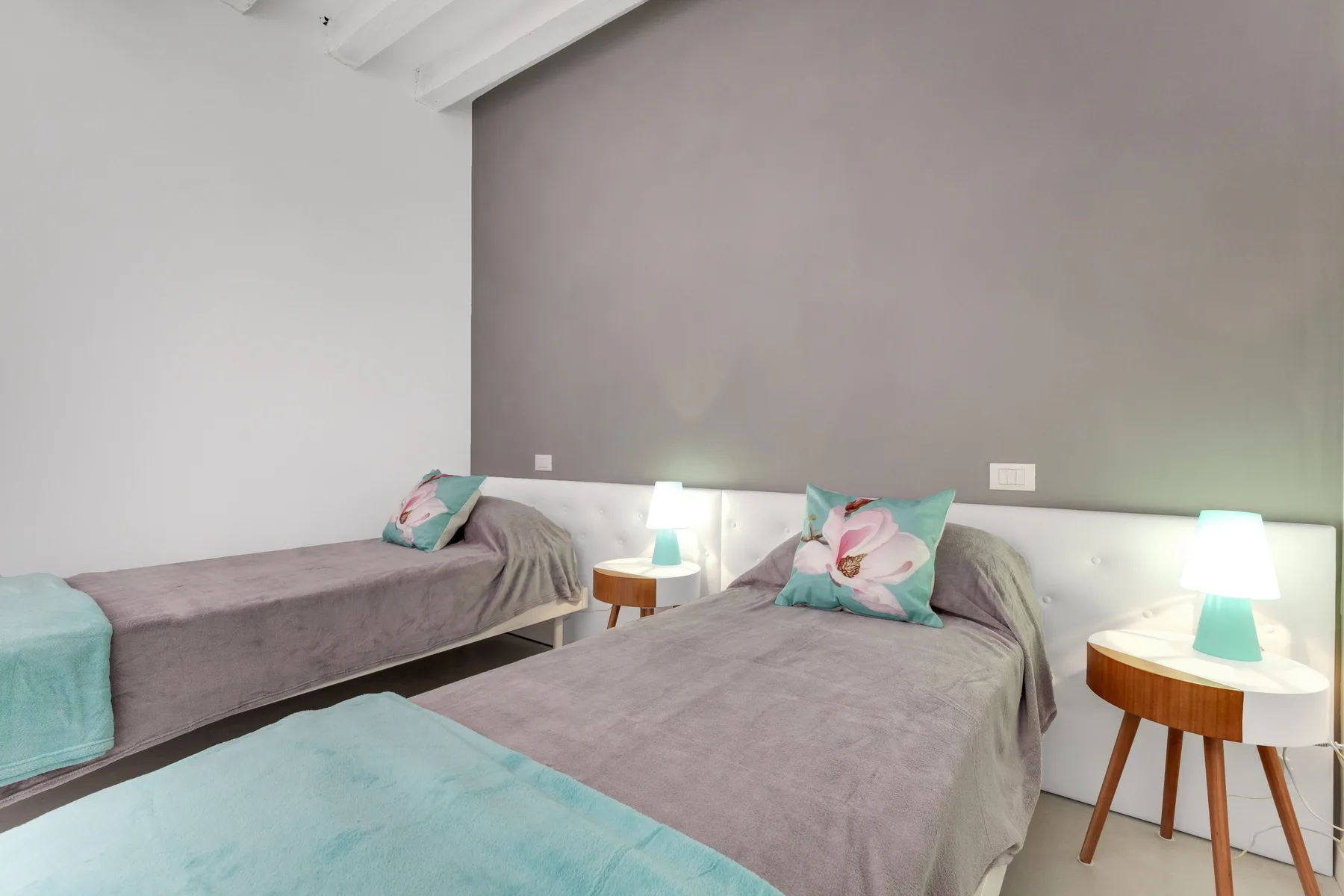 Dormitorio con dos camas, detalles turquesa y lámparas de noche.