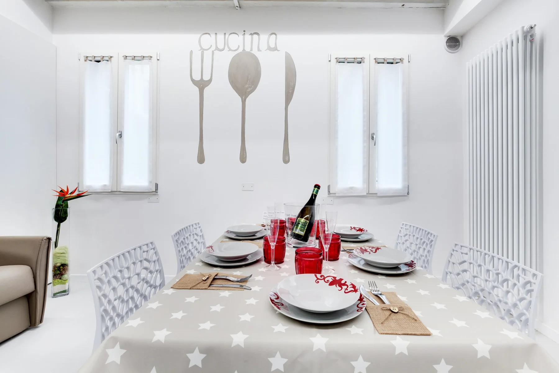 Una mesa de comedor está puesta bajo adornos de pared en una habitación luminosa.