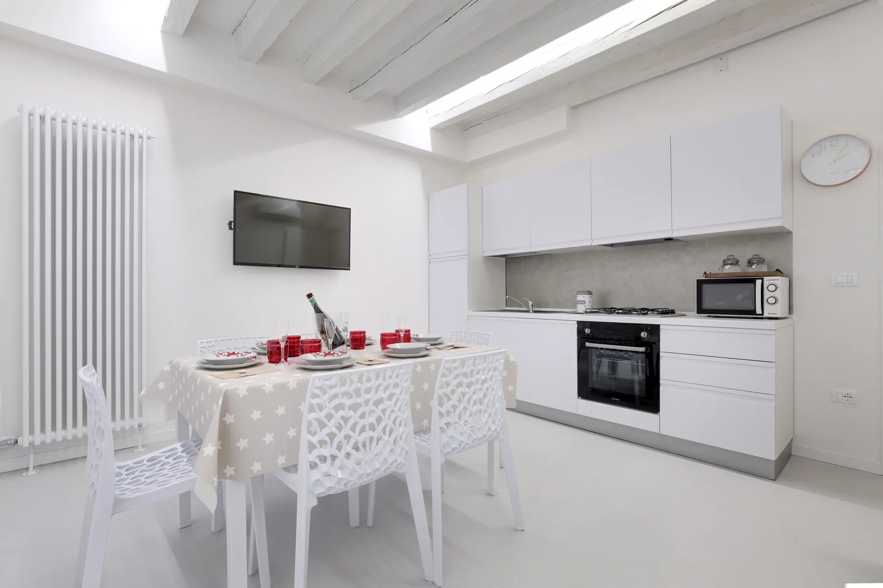 A bright dining area beside a compact kitchen, with a table set for a meal.
