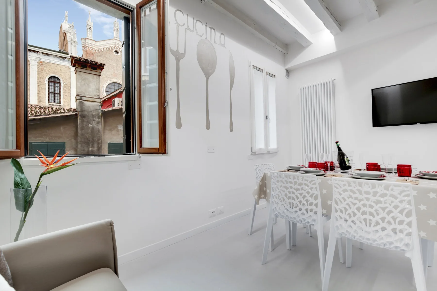 Un comedor luminoso con una mesa blanca y sillas junto a una ventana abierta.