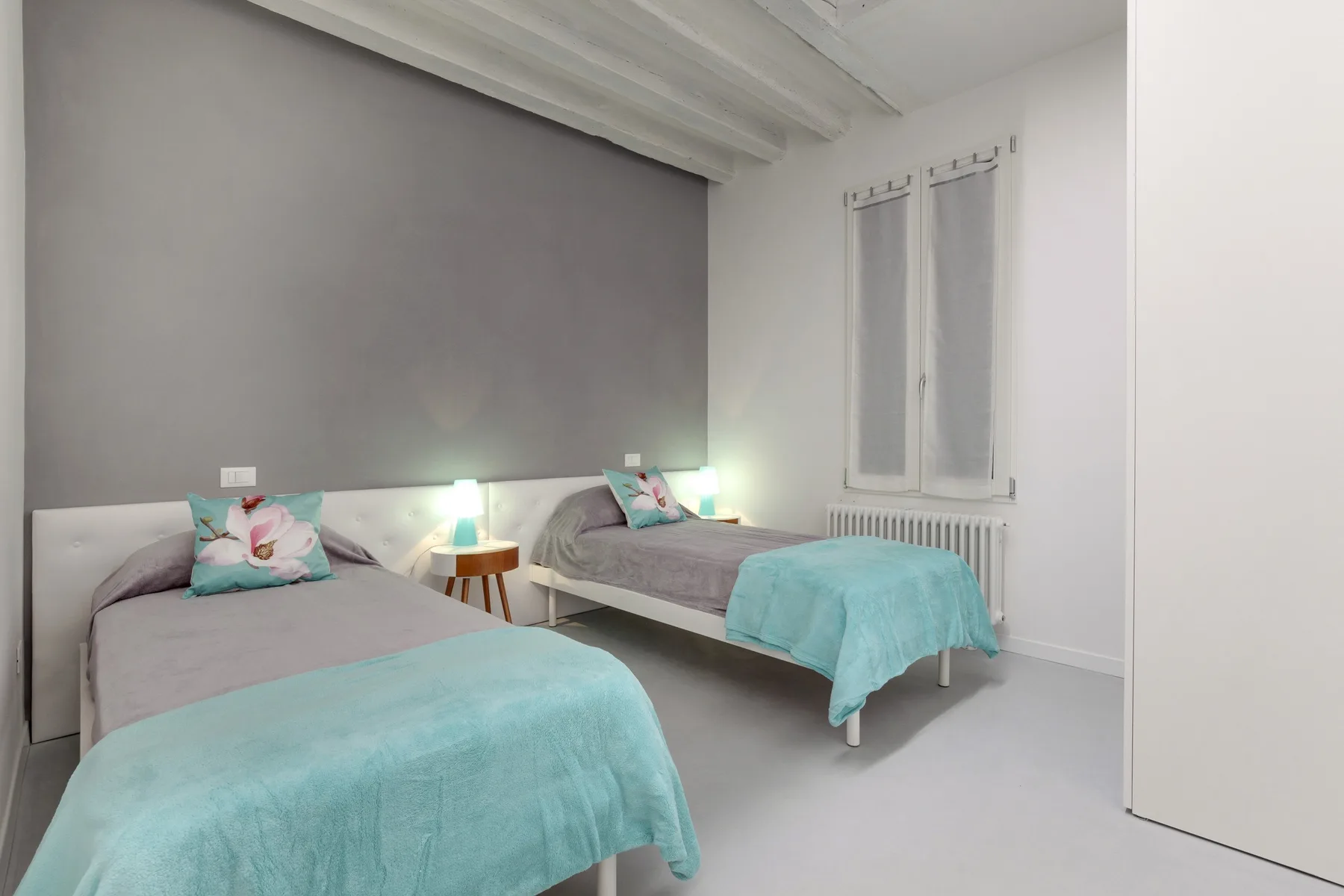 Un dormitorio con dos camas vestidas con ropa de cama gris y turquesa.