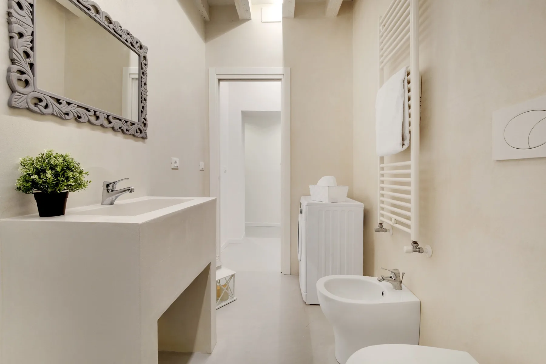 Un baño luminoso con lavabo, bañera y calentador de toallas.