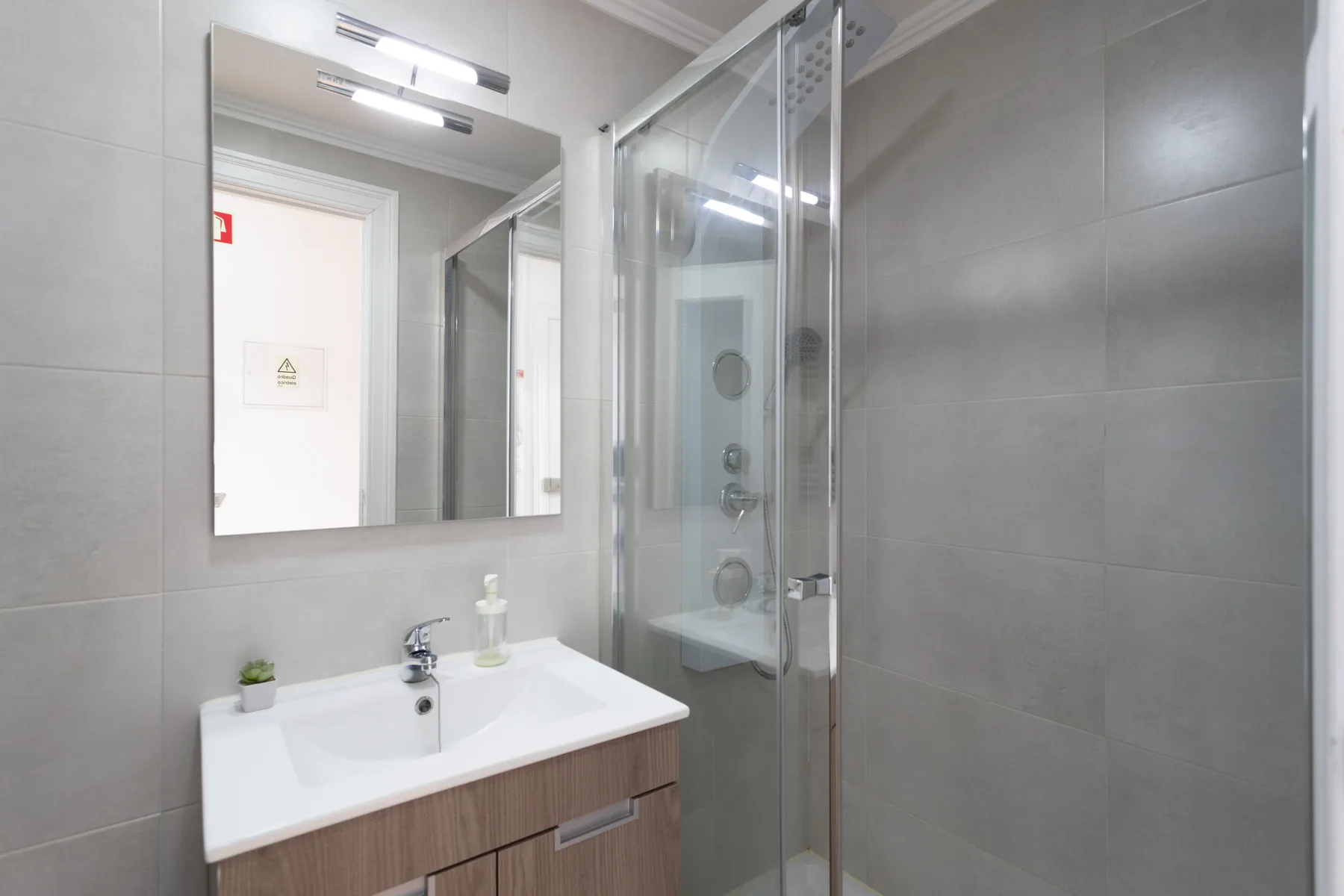 Un baño alicatado con un lavabo blanco y una ducha de cristal.