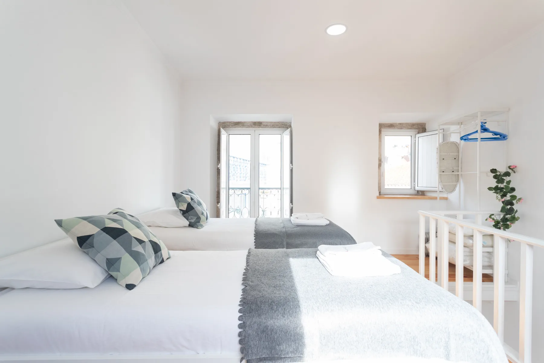 Un dormitorio luminoso con dos camas vestidas con ropa de cama blanca.