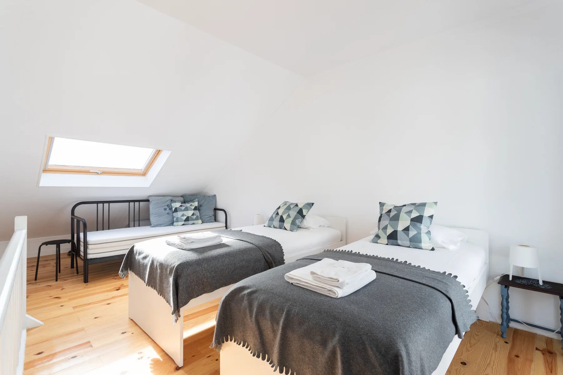 Un dormitorio luminoso con dos camas y una claraboya.