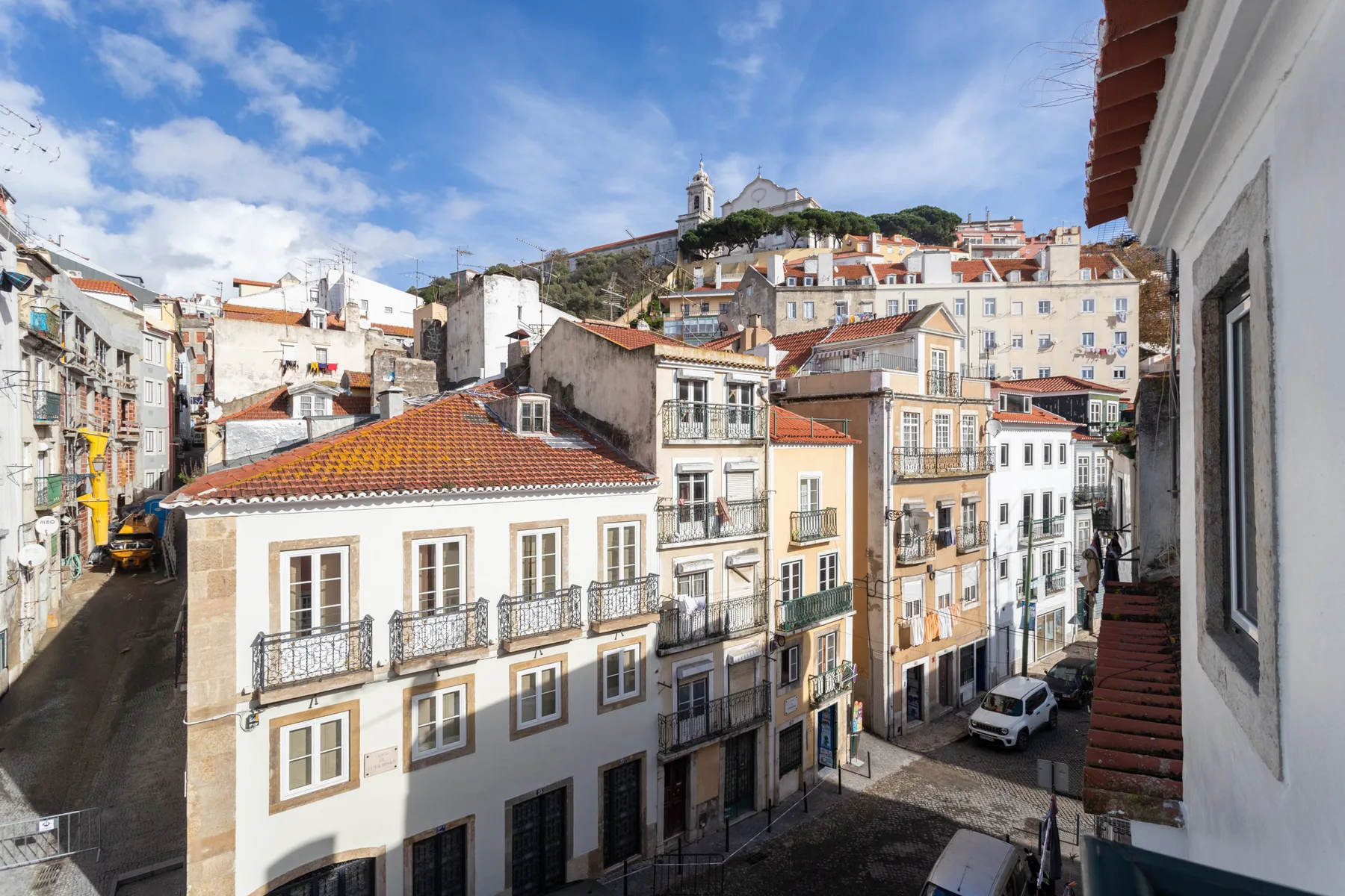 Una calle de Lisboa bordeada de edificios y con una iglesia en lo alto de una colina.