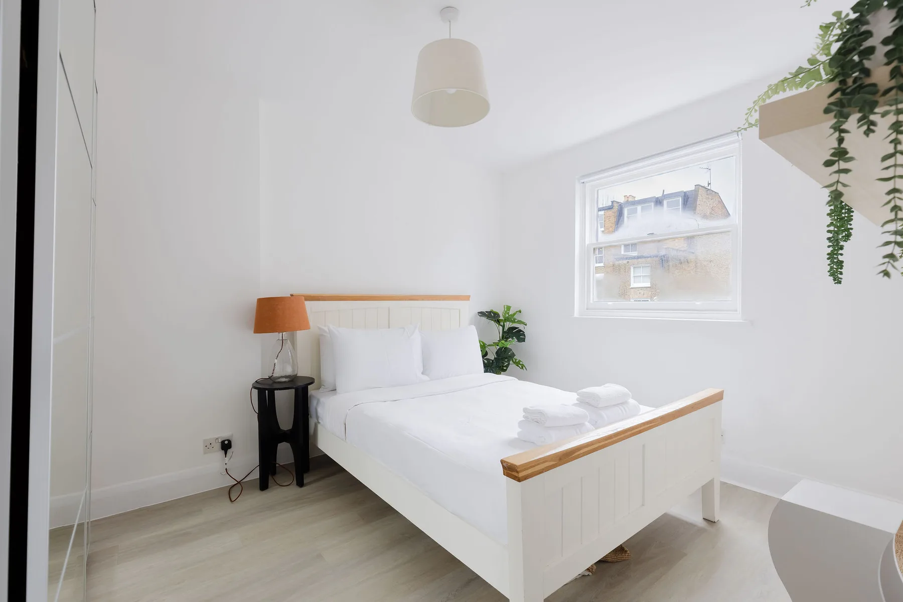 Un dormitorio luminoso con una cama blanca y una ventana.