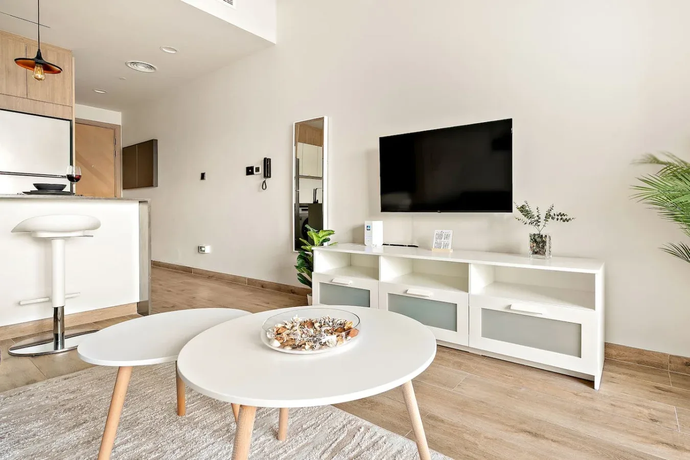 Bright open-plan living area with a television above a white media console.