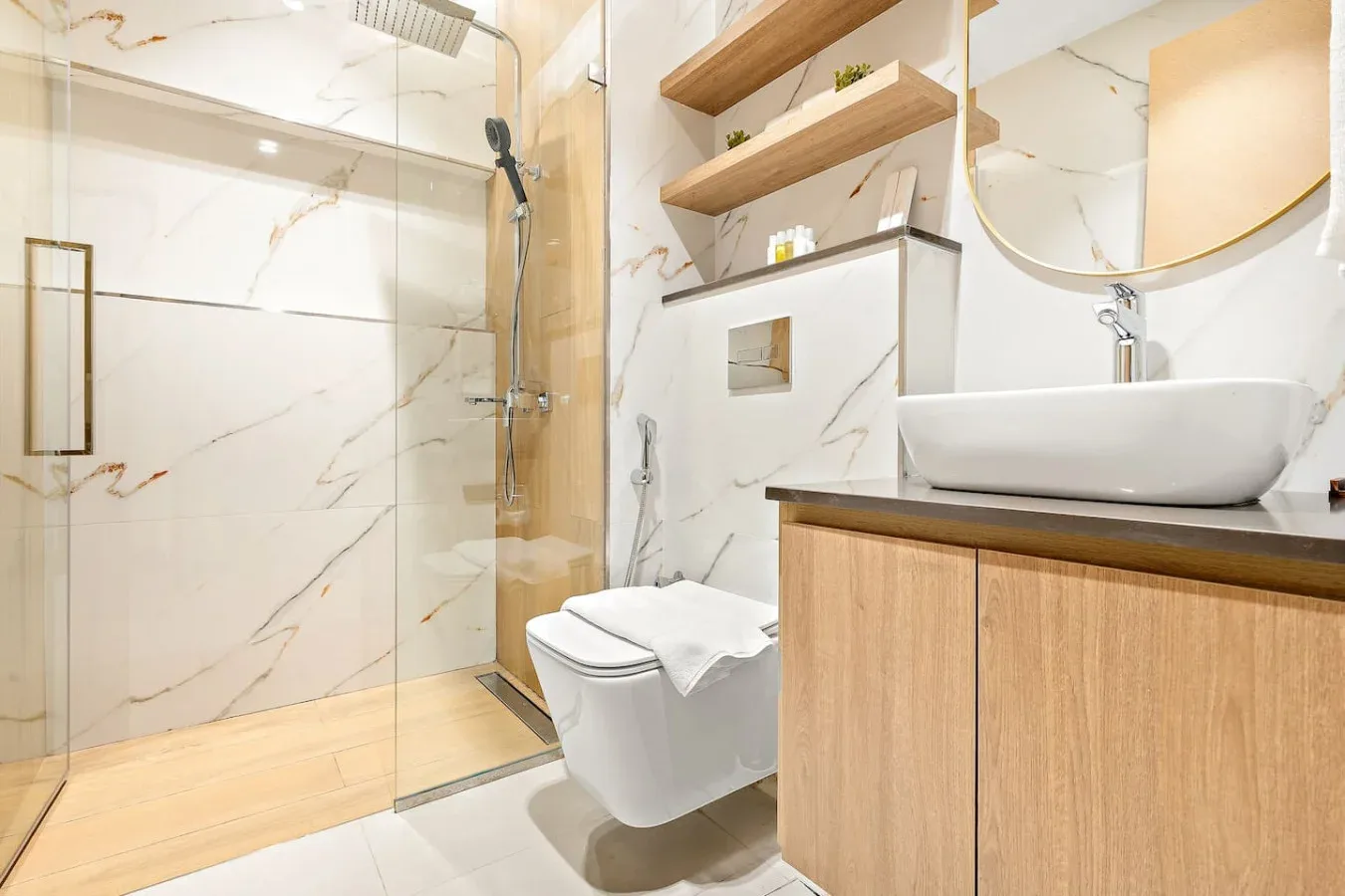 A bright bathroom with a glass shower, toilet, and vanity.