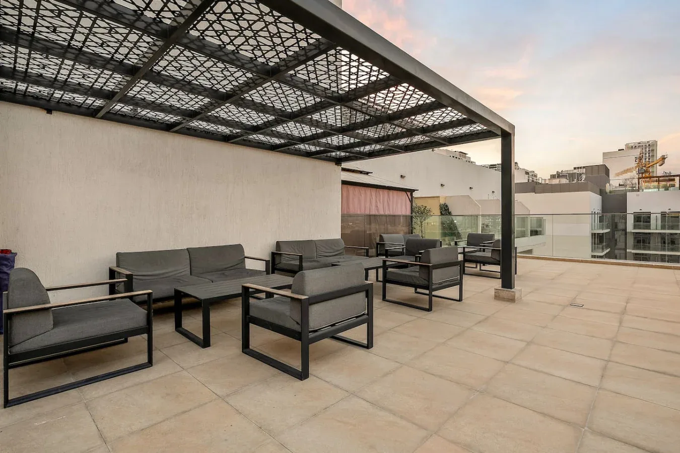 An outdoor terrace has seating beneath a metal canopy.