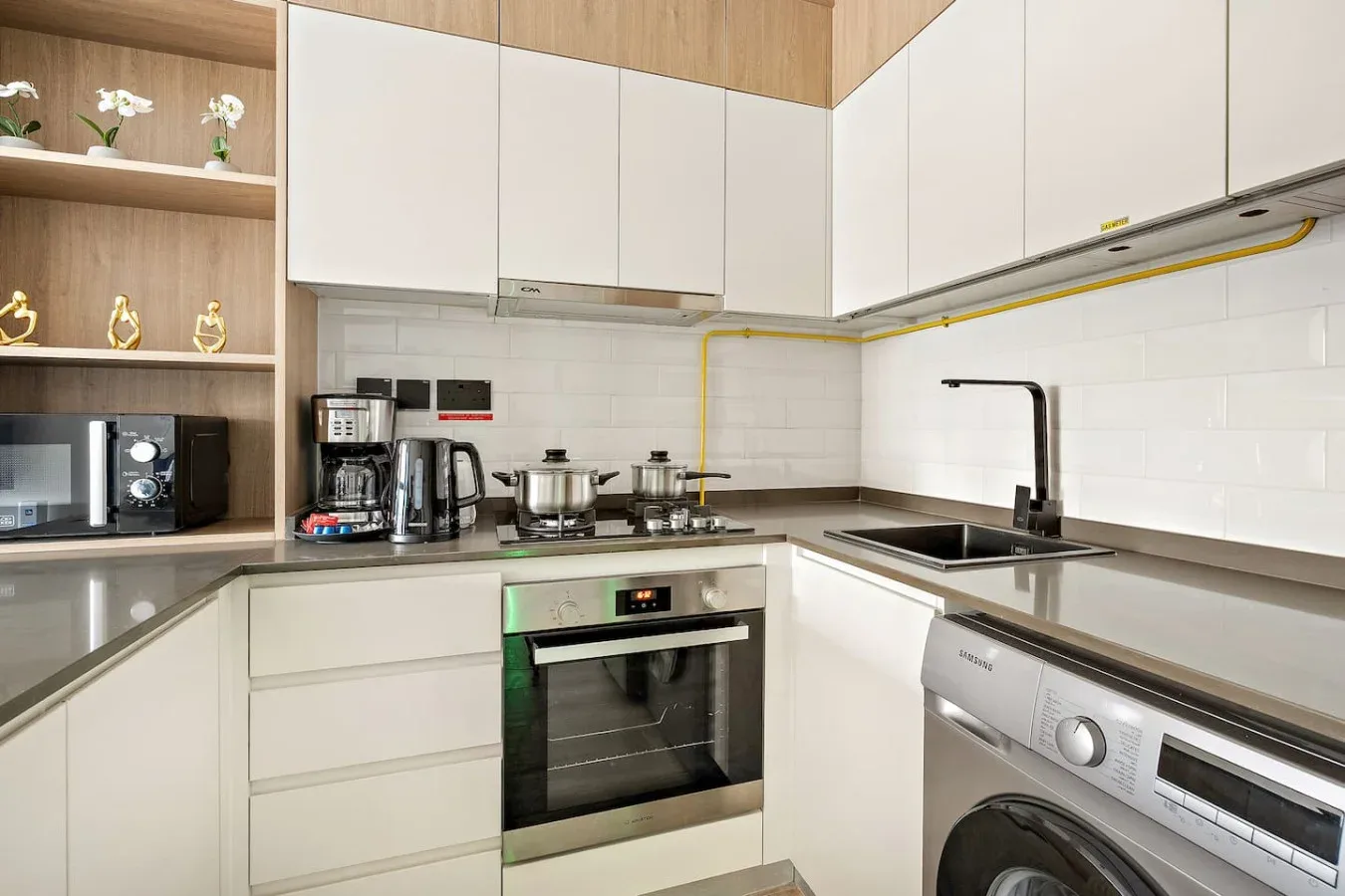 A modern kitchen with white cabinets, a cooktop, and a sink.