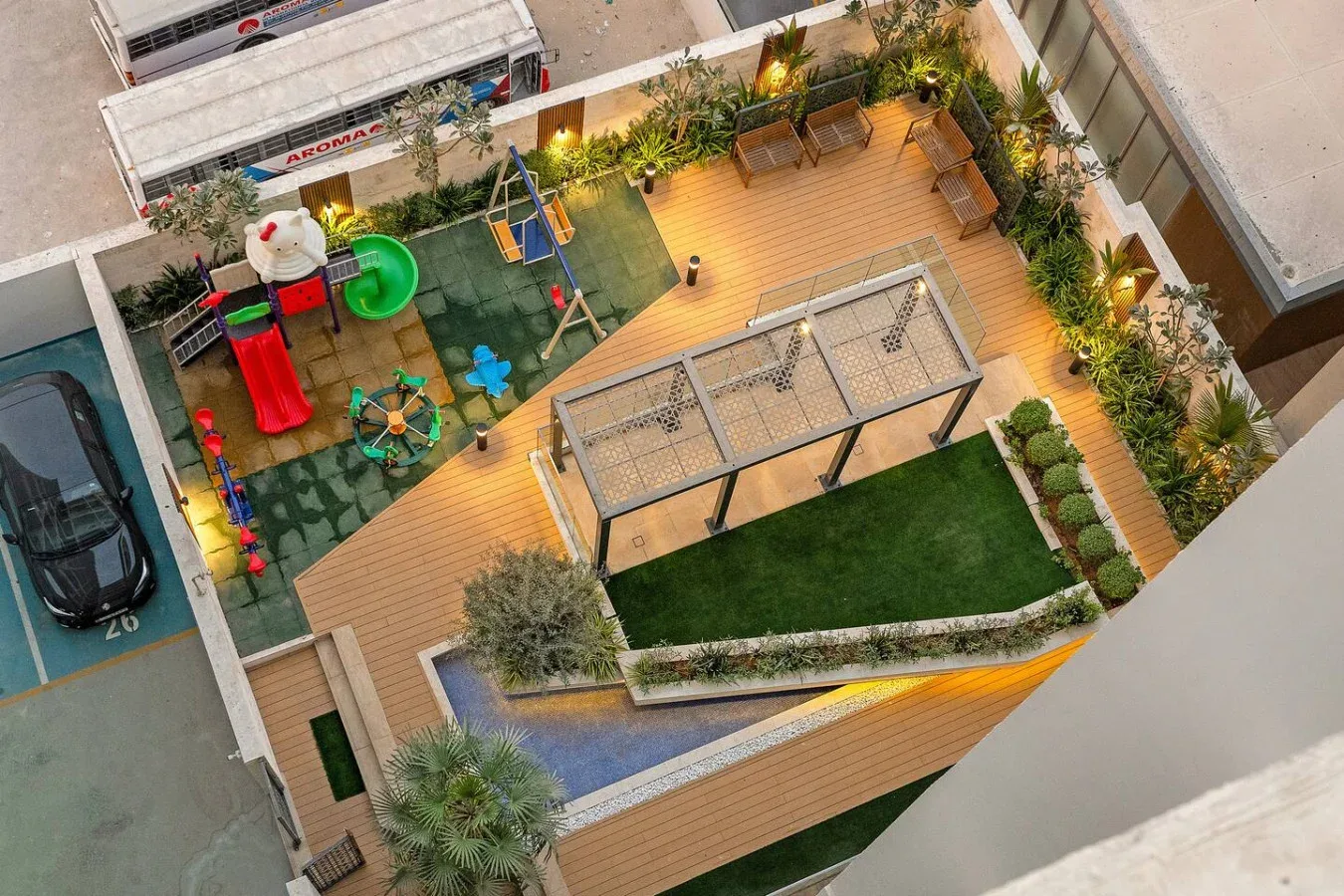 An overhead view of a landscaped rooftop terrace with wooden decking, seating, and a play area.