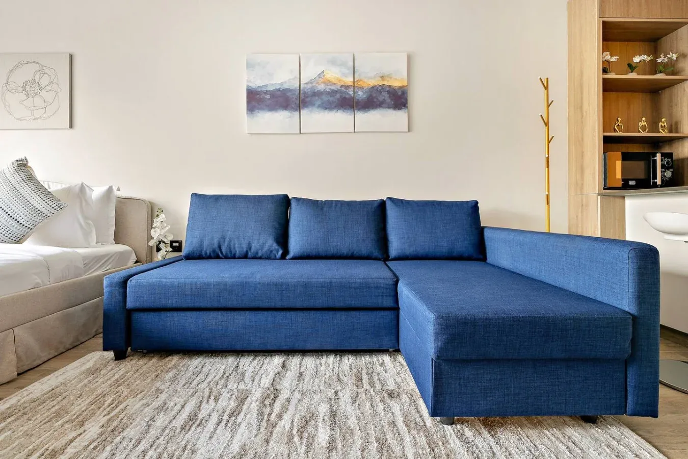 A living room with a blue sectional sofa and a light-colored rug.