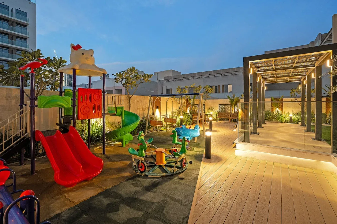 An outdoor playground and illuminated walkway sit beside landscaped garden areas.