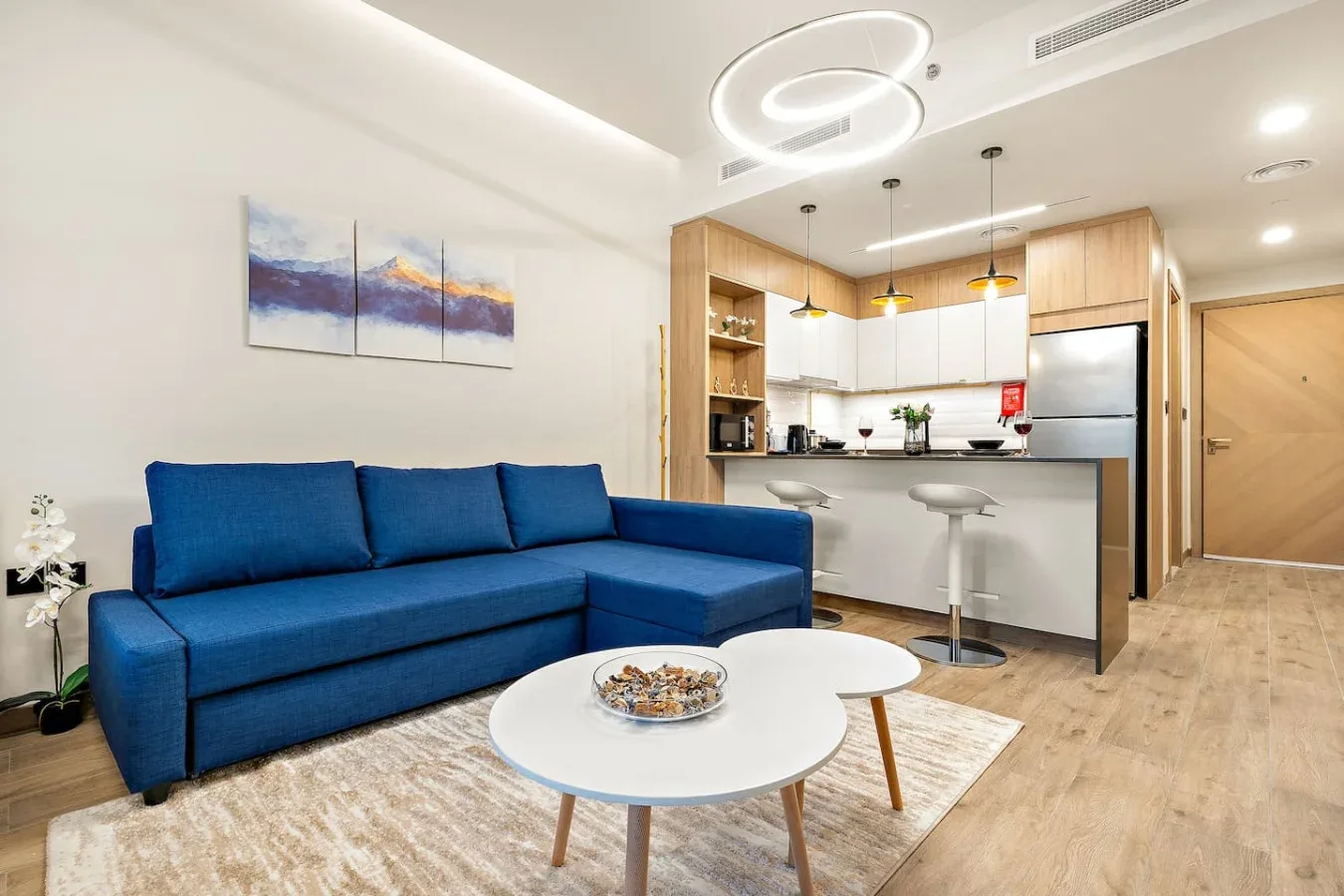 A living room with blue seating and a dining counter beside the kitchen.