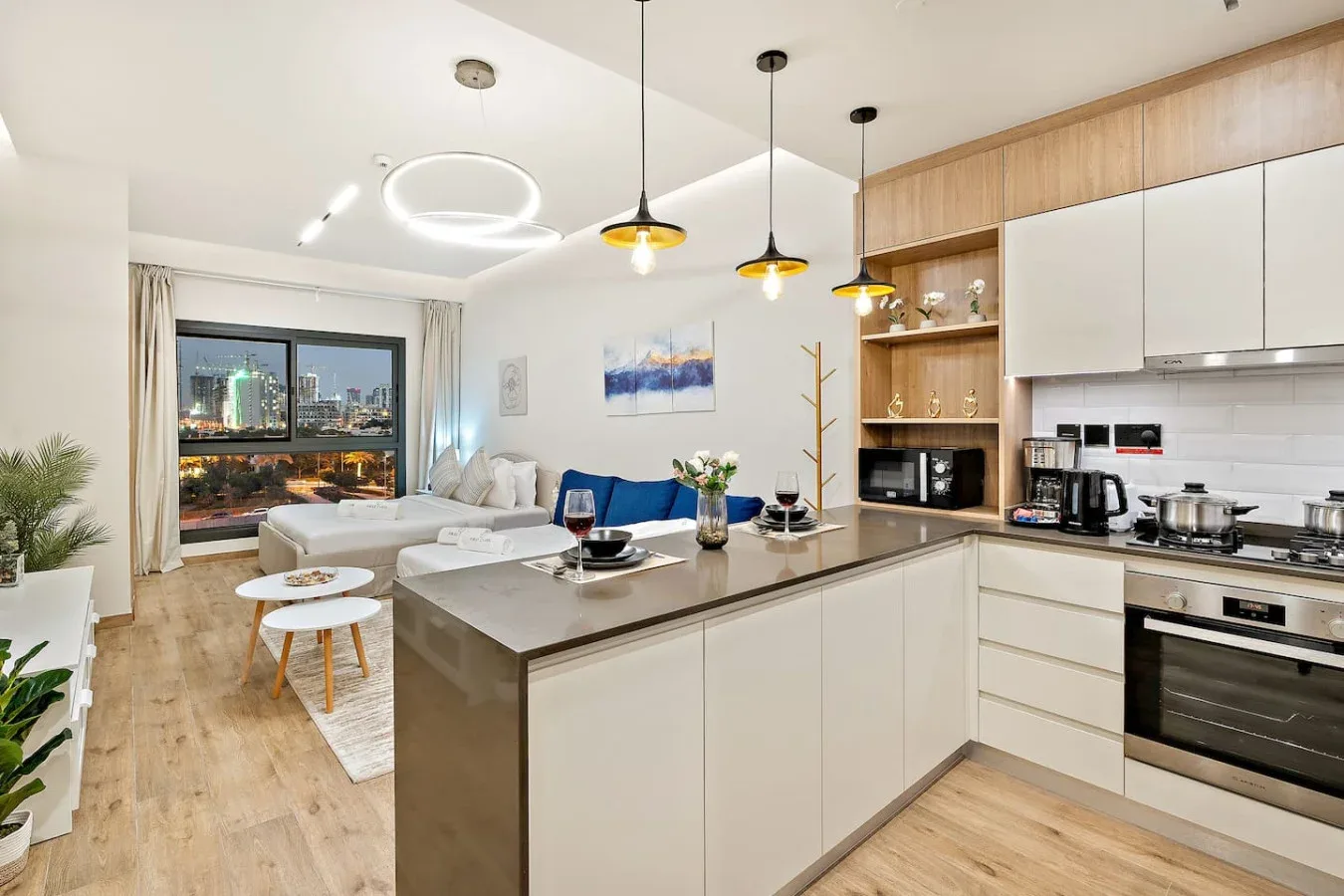An open-plan kitchen and living area with a central island and seating by the windows.