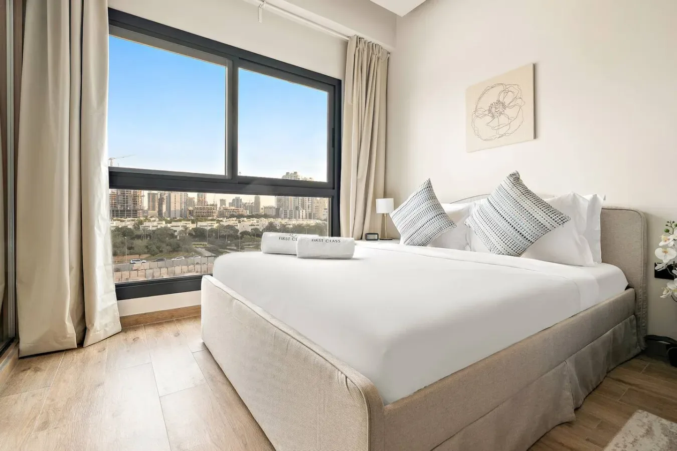 A bright bedroom with a neatly made bed beside a large window.